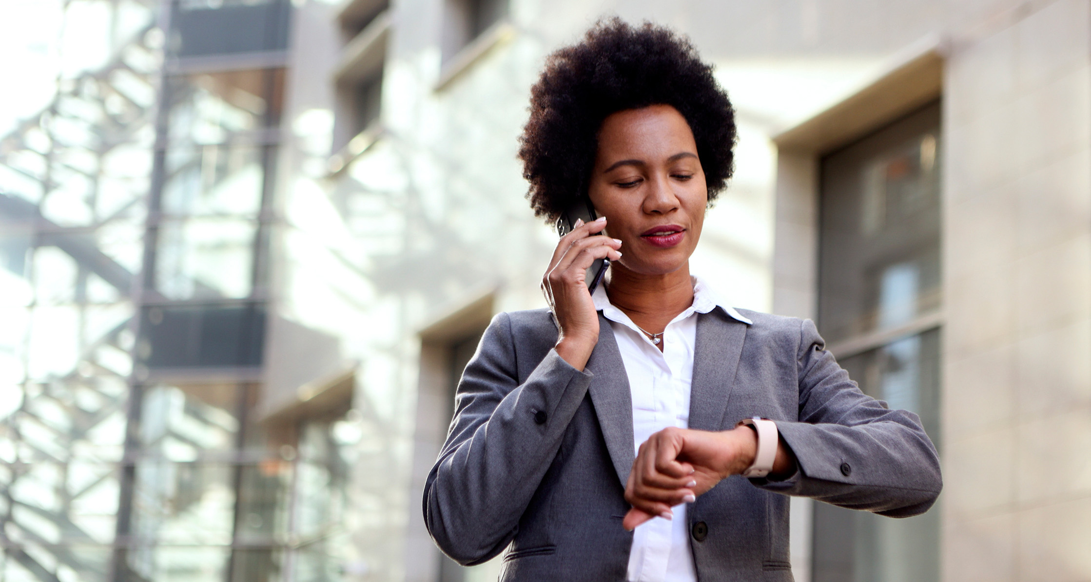 A woman is checking her watch while on a phone call.