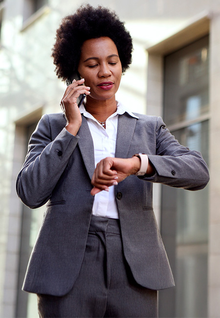 A woman is checking her watch while on a phone call.
