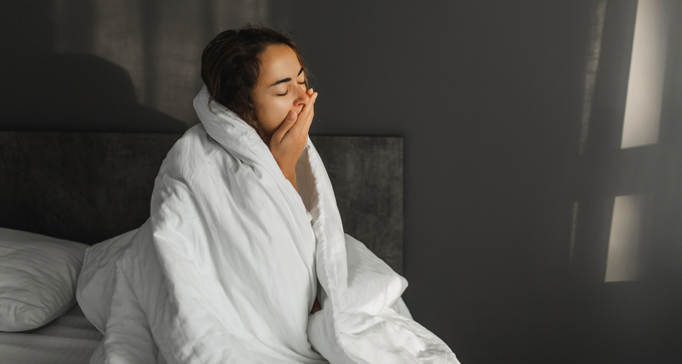 A woman who is yawning struggles to wake up in the morning.