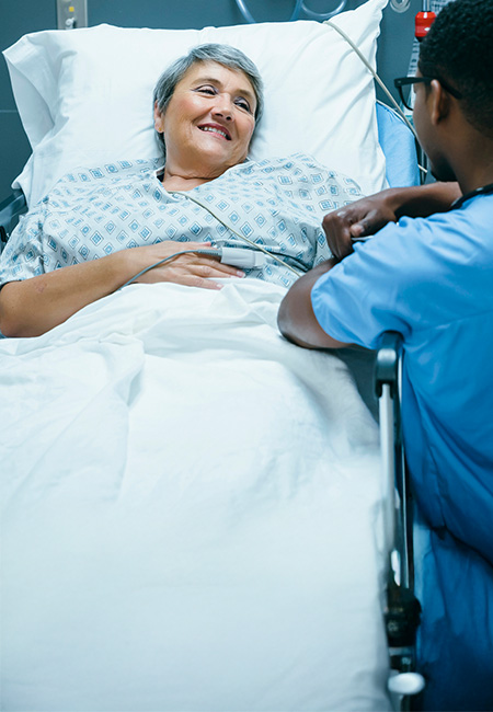 A nurse talking to a patient after surgery in a hospital bed.