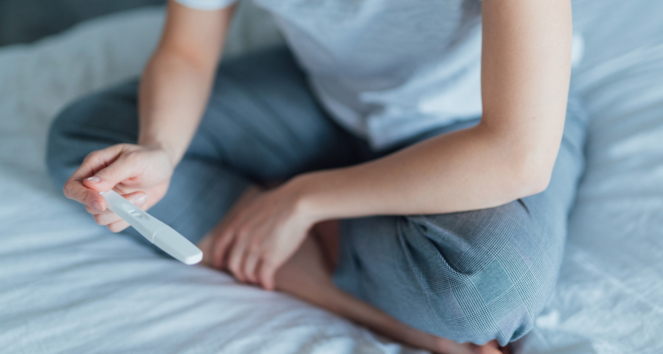 A service member sitting on her bed with a home pregnancy test.