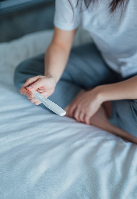 A service member sitting on her bed with a home pregnancy test.