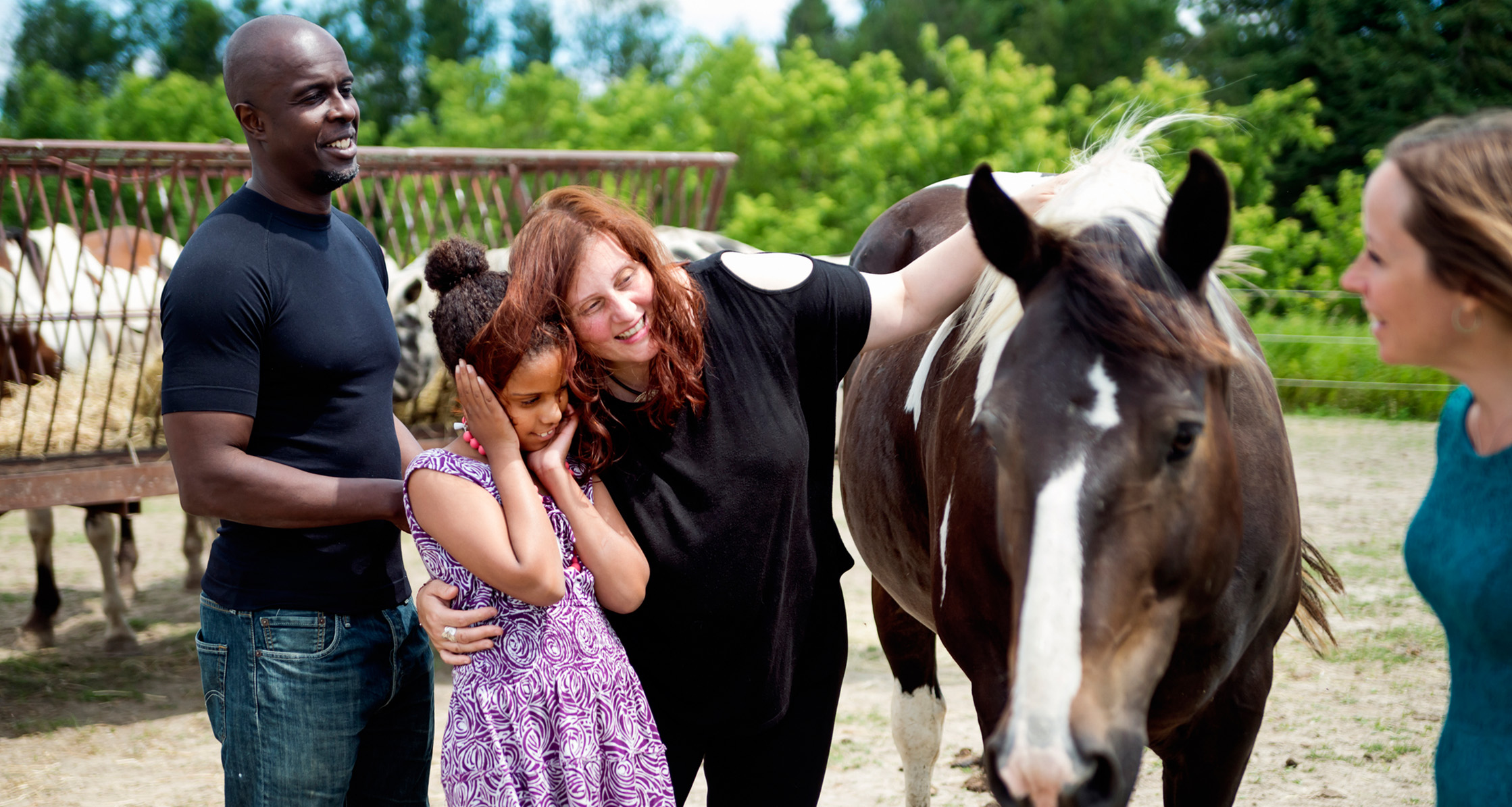 A young girl with autism is bonding with a service horse while her parents are nearby offering support.