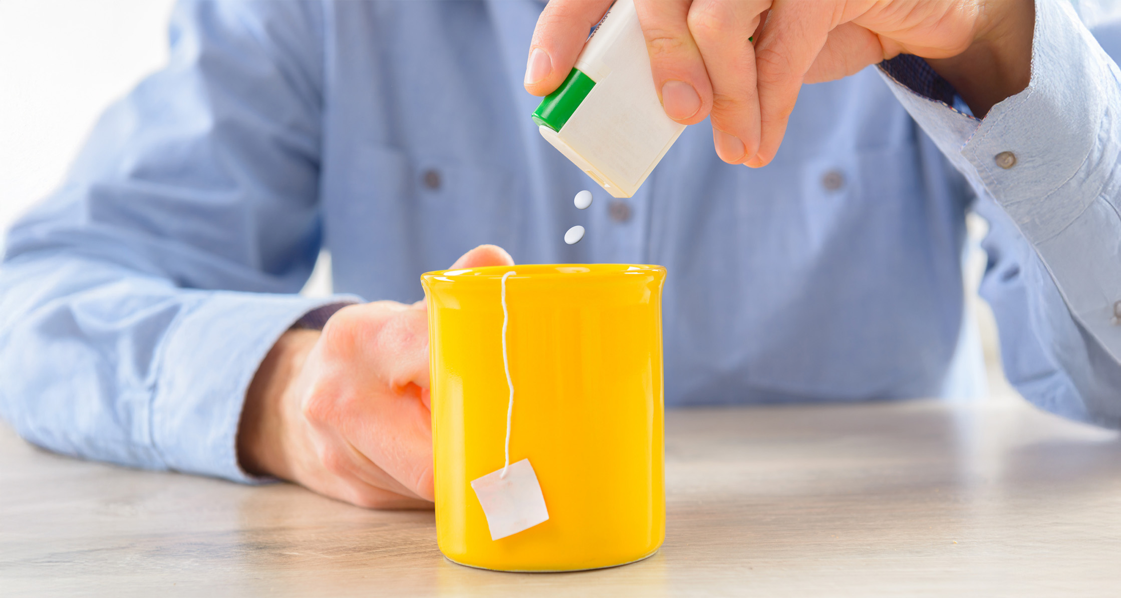 Close-up of a person using saccharin pills in hot tea.