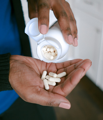 A person pours probiotic capsules into their hand.