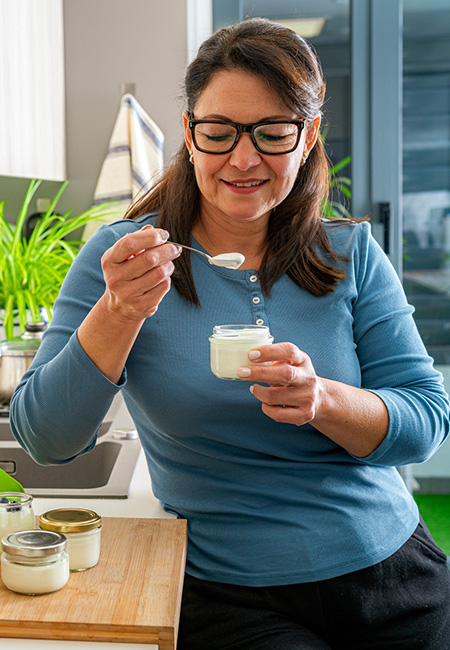 A woman enjoys homemade yogurt in her kitchen.