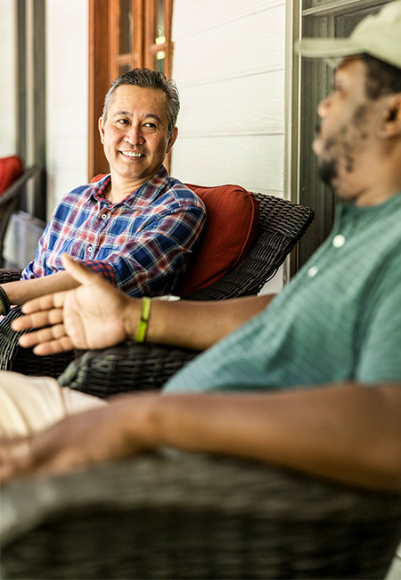Senior U.S. military Veterans are talking on the front porch of a suburban home.