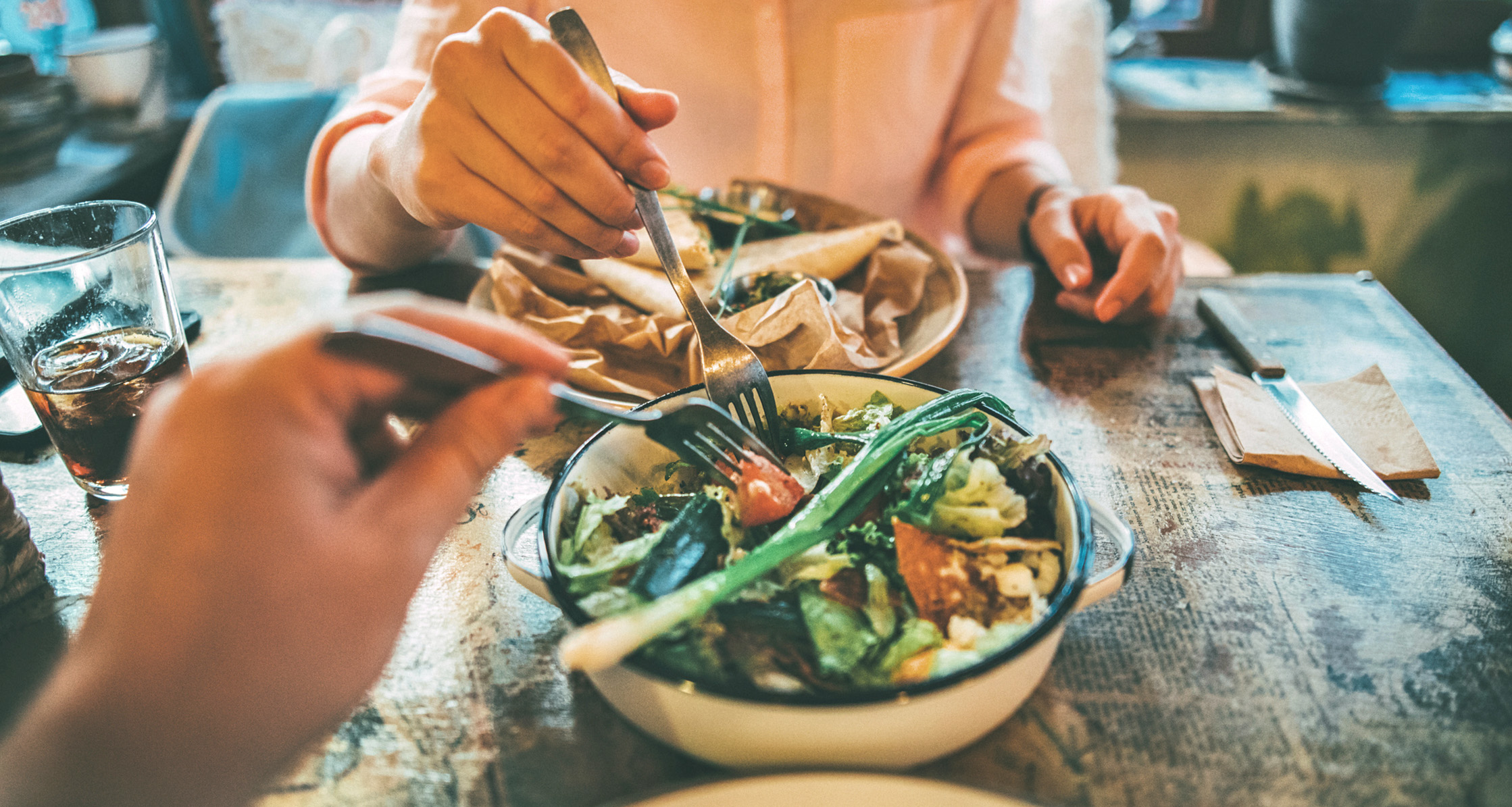 A couple shares a salad at a restaurant for portion control.