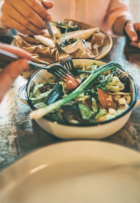 A couple shares a salad at a restaurant for portion control.