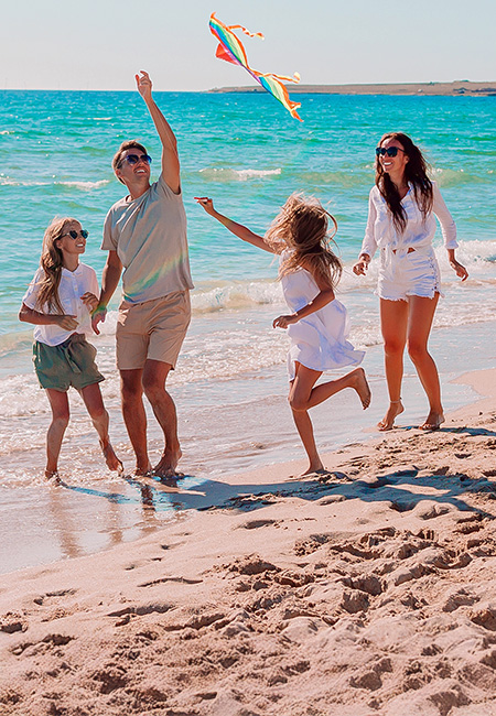 A family is flying a kite at the beach.