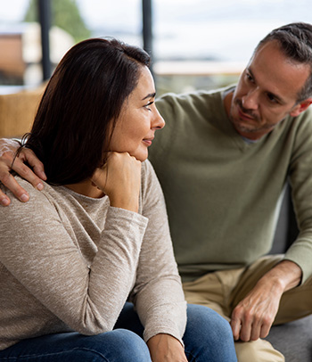 A man is comforting his wife at home.