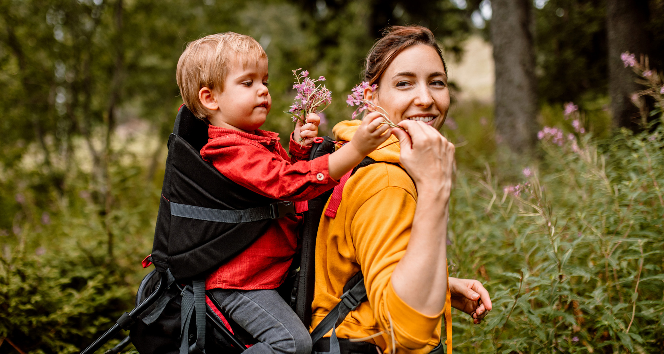 A mother hikes with her son, picking spring flowers in the woods.