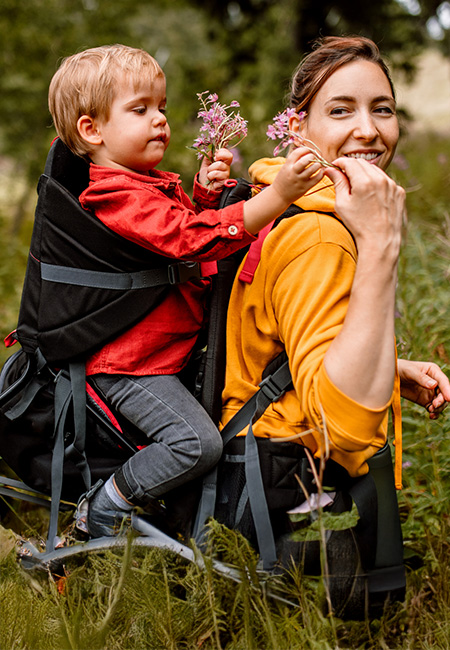 A mother hikes with her son, picking spring flowers in the woods.