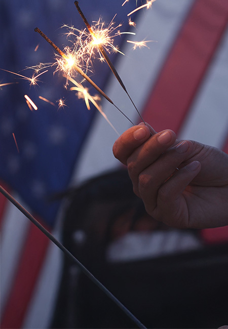 Happy 4th of July, celebrating with sparklers, fireworks, and the American flag.