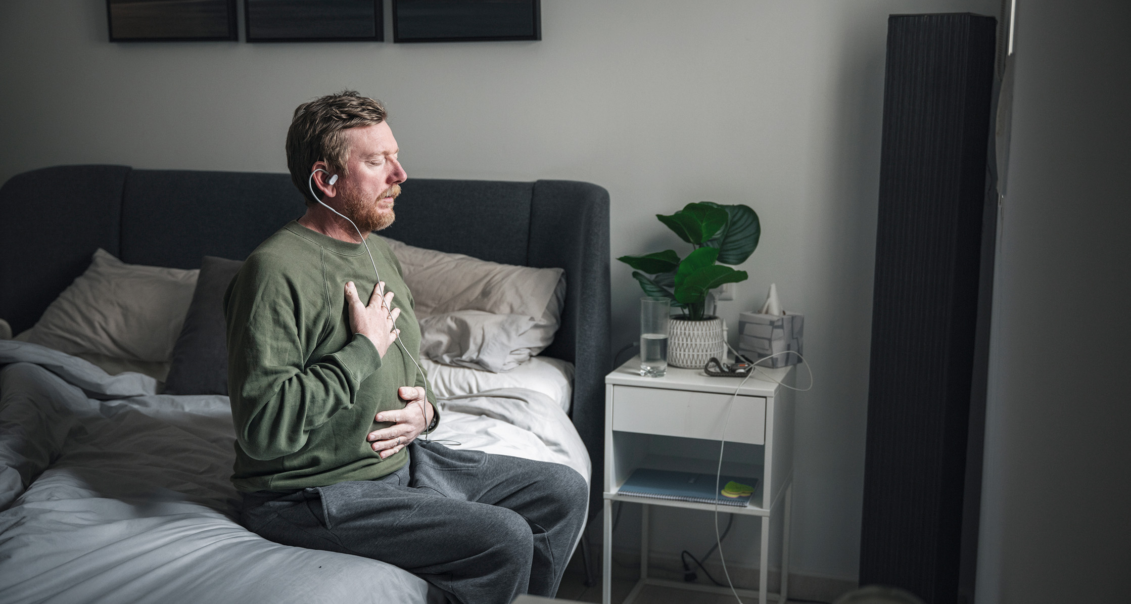 A mature man uses a vagus nerve stimulation device in his bedroom.