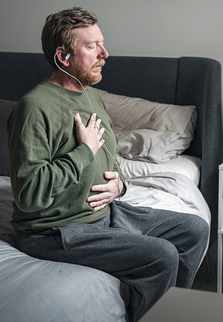 A mature man uses a vagus nerve stimulation device in his bedroom.