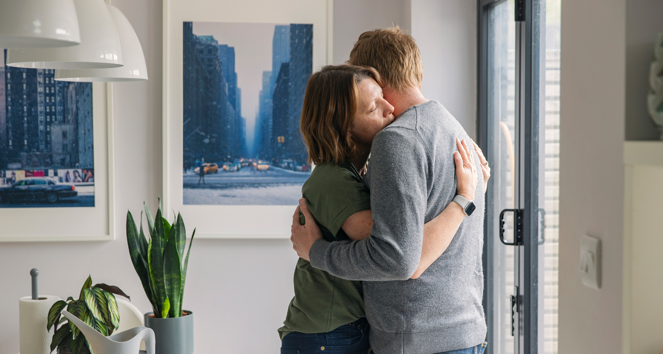 A military couple shares a warm embrace in their home.