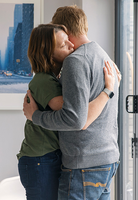 A military couple shares a warm embrace in their home.