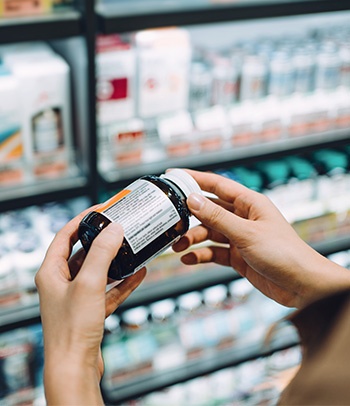 A person examines the ingredients on a supplement label.