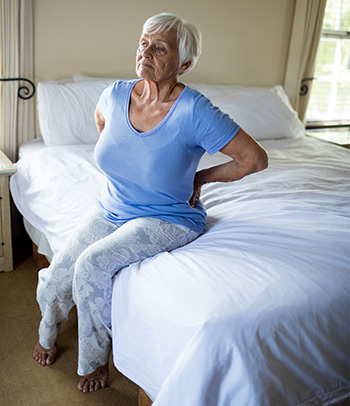 A woman in bed with chronic back pain.