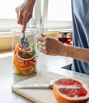 A woman prepares a refreshing citrus-infused water with grapefruit, lemon and mint.