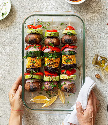 Preparing vegan kebab with various vegetables and shiitake mushrooms.