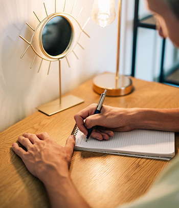 A person writing in a journal at a desk.