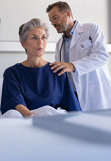 Physician checking a woman’s lung sounds through a stethoscope.