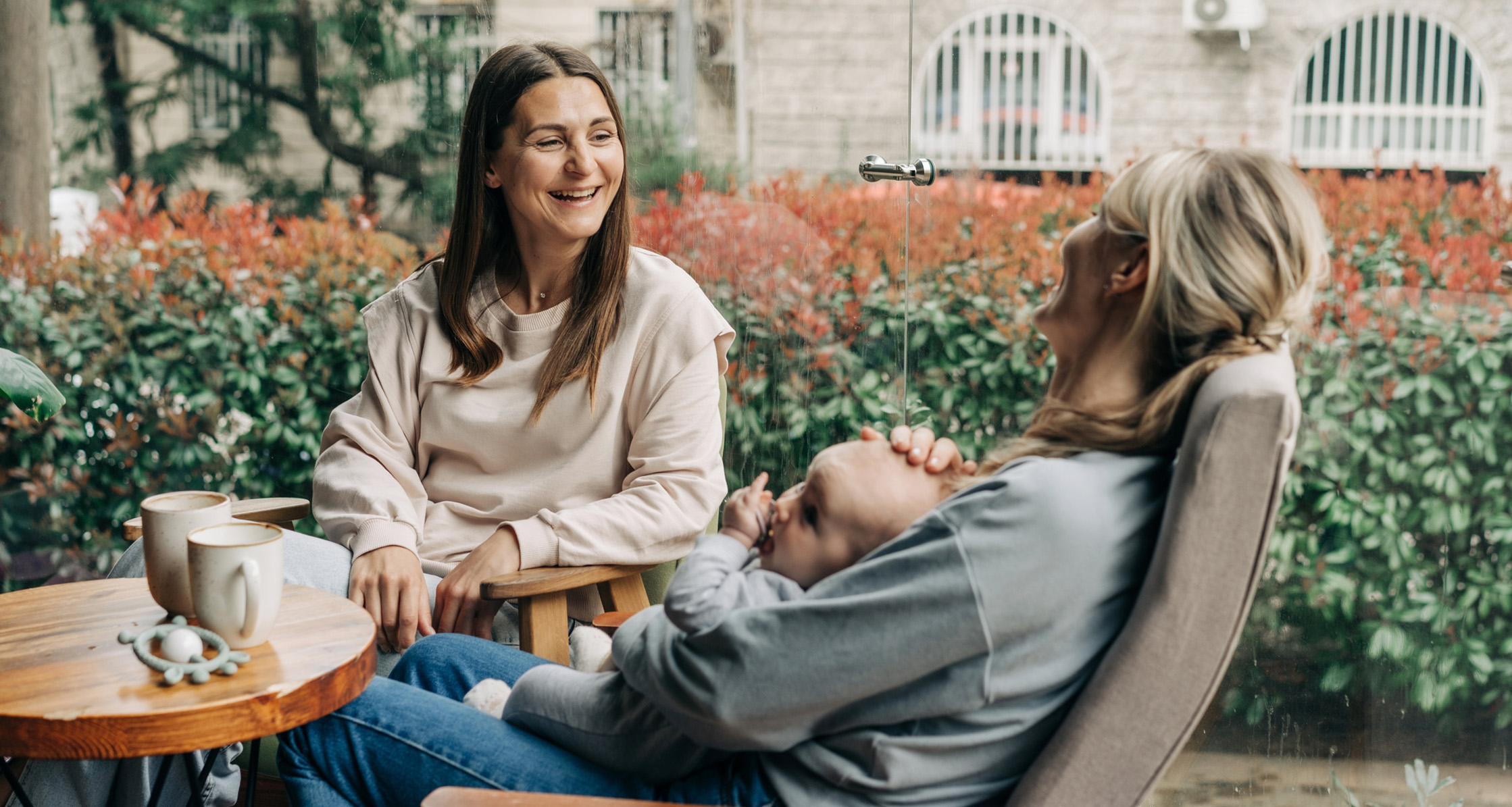 Two military spouses catch up over coffee while one holds a baby.