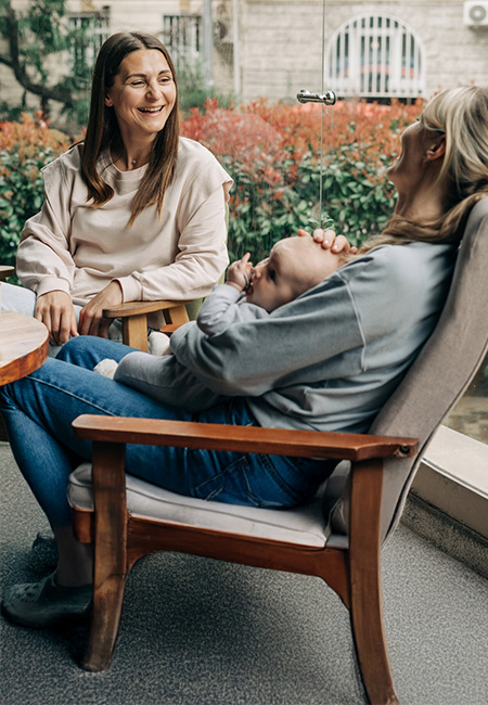 Two military spouses catch up over coffee while one holds a baby.