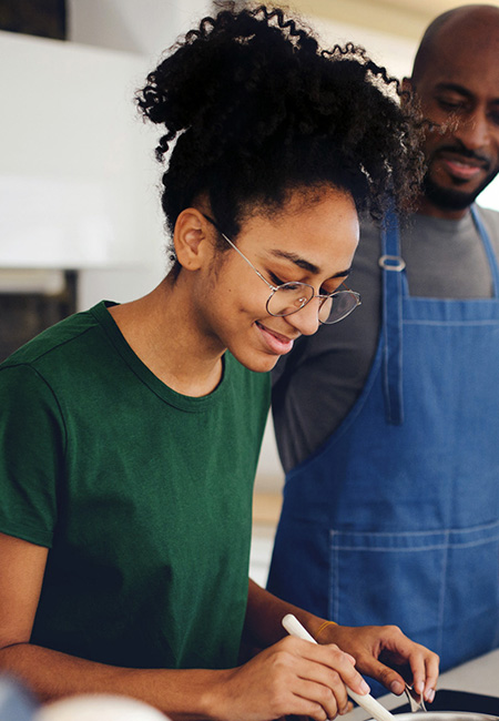 A father prepares food with his teenagers at home.