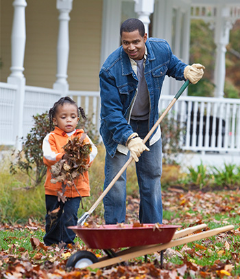 Father and child raking leaves.