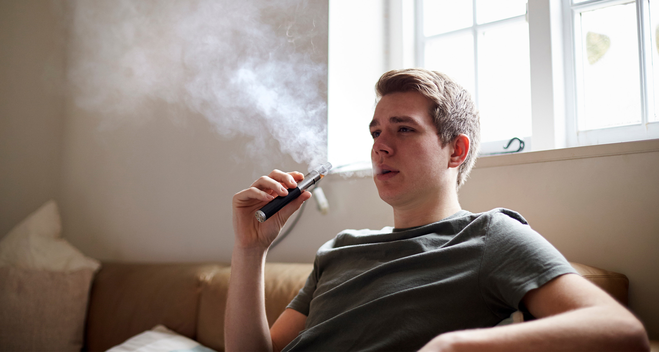 Young person vapes in his living room.