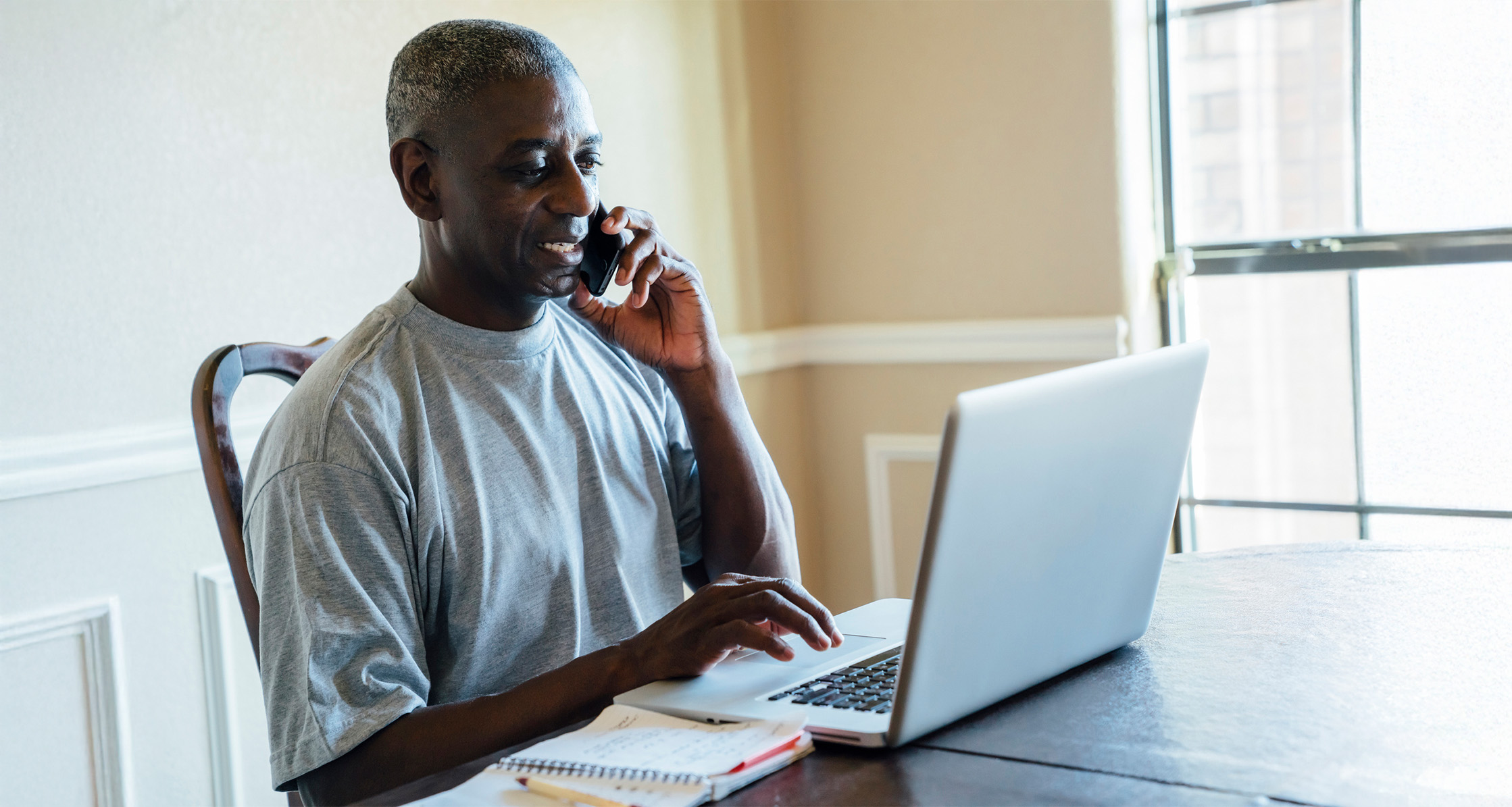 A retired Veteran uses a laptop and phone for MyHealtheVet portal.