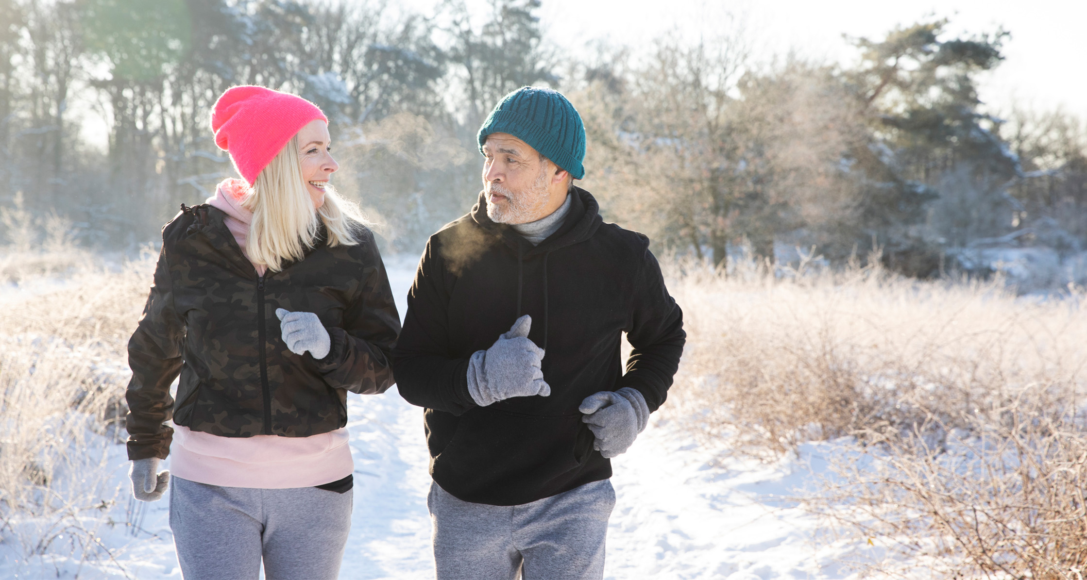 A retired couple keeps active by jogging in the snow.