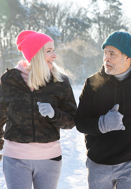 A retired couple keeps active by jogging in the snow.