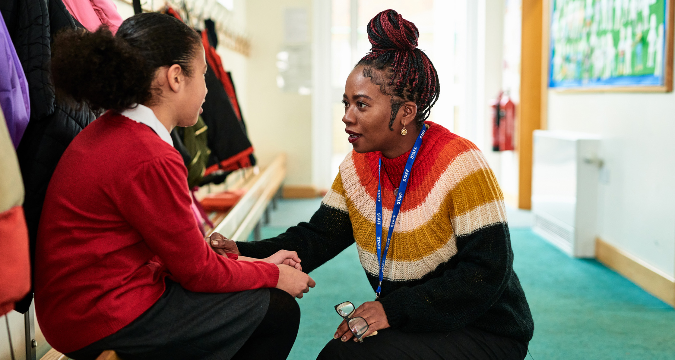 Teacher comforts a student in school hallway.