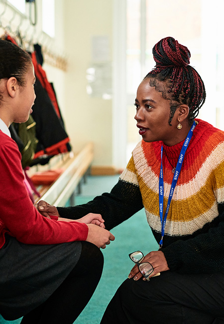 Teacher comforts a student in school hallway.