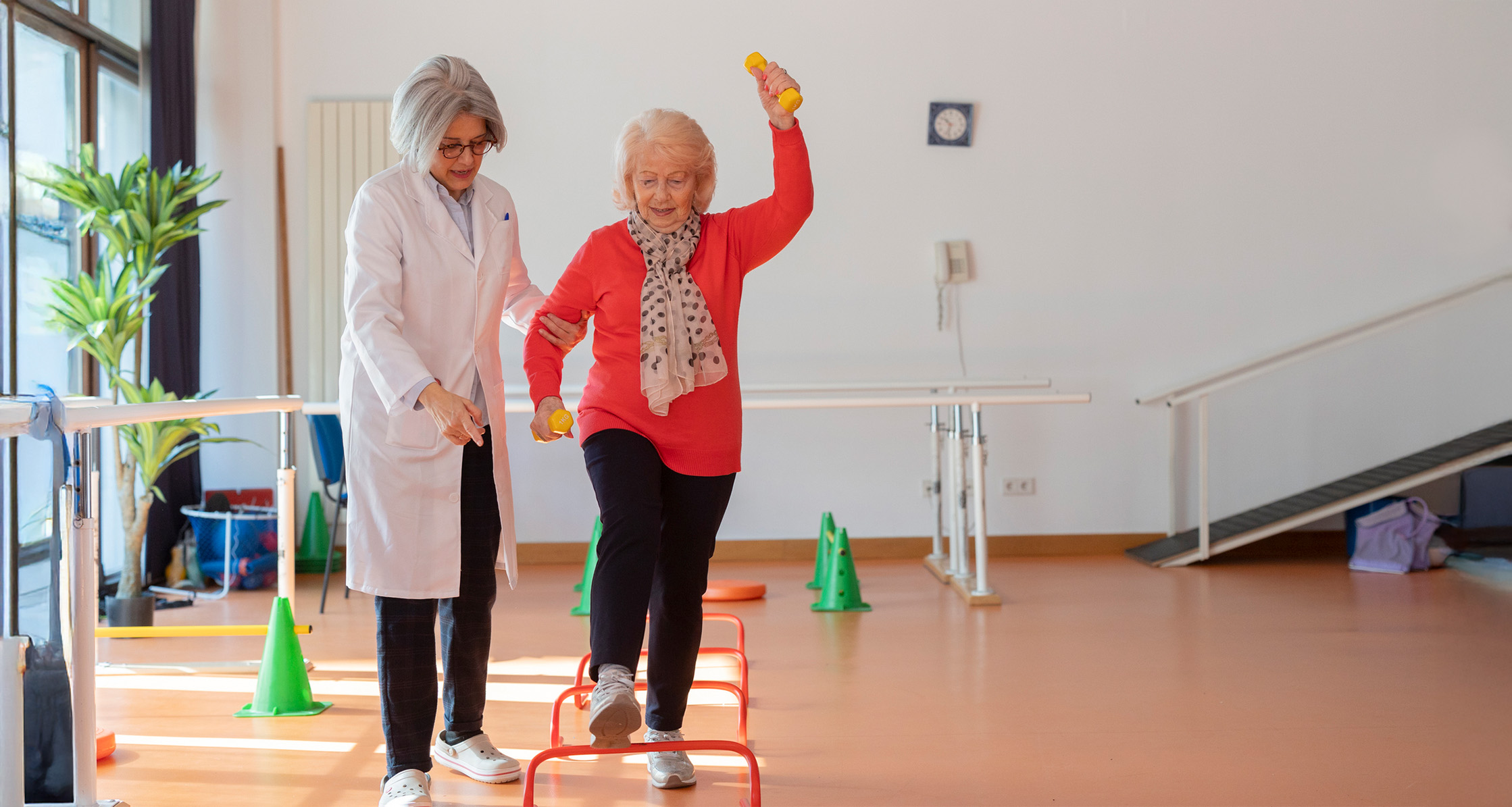 Older woman does a balance exercise with a therapist’s support.