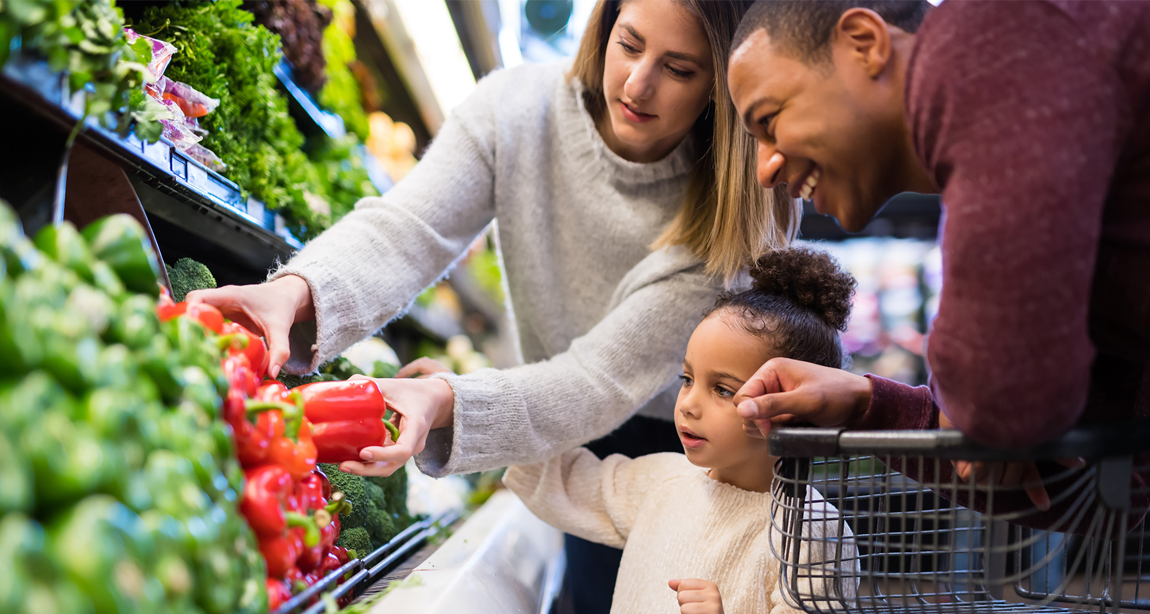Parents show their daughter how to select vegetables.