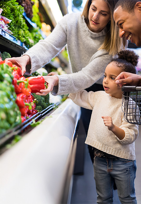 Parents show their daughter how to select vegetables.