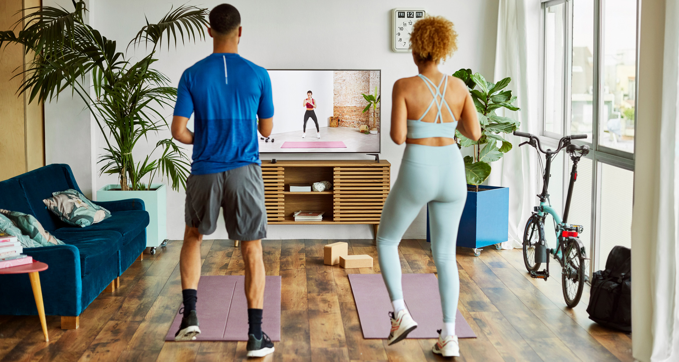 A couple participates in an online workout class at home.