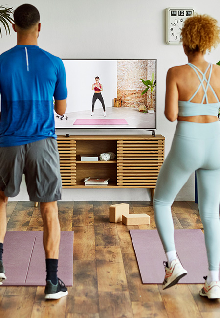 A couple participates in an online workout class at home.