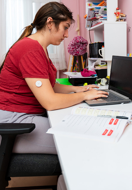 Teenage girl wears a diabetes monitor.