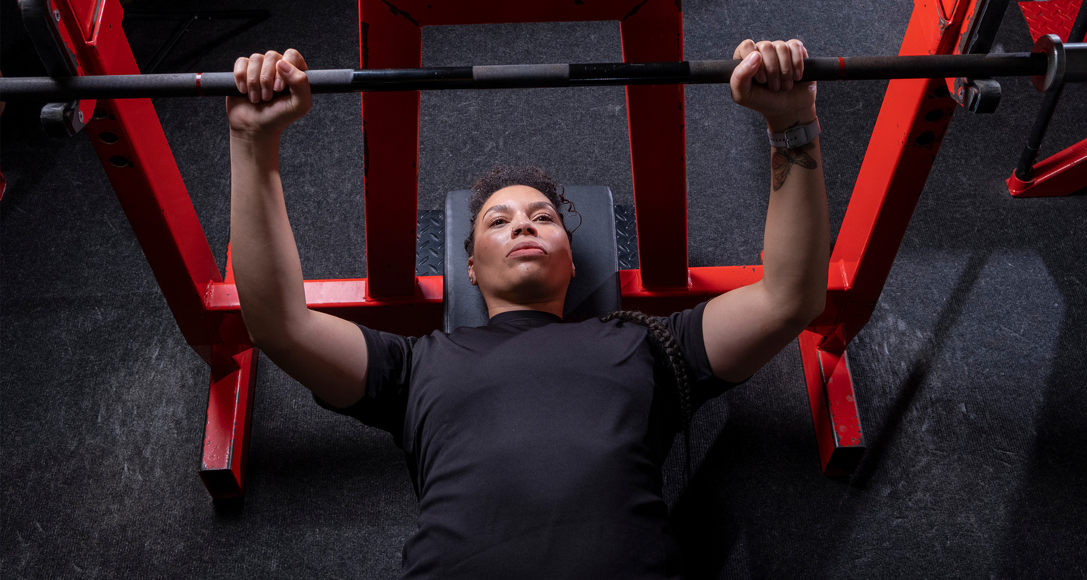 Person performs bench press exercise on gym equipment.
