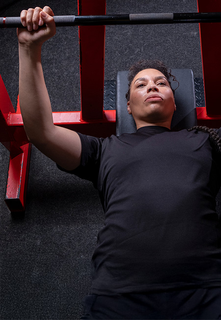 Person performs bench press exercise on gym equipment.