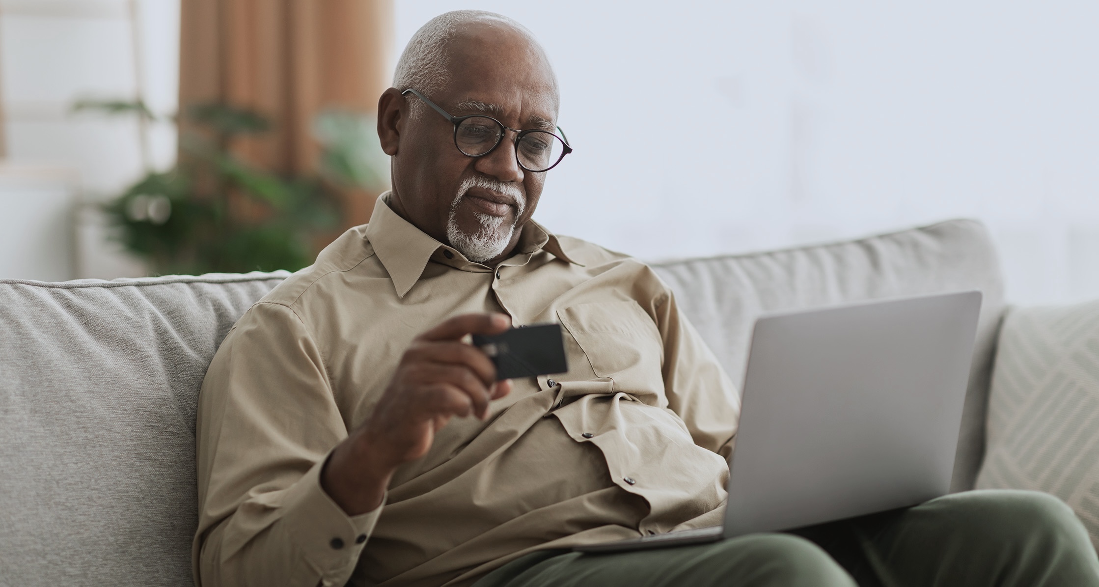 Veteran uses a laptop and holding a credit card to place an order.