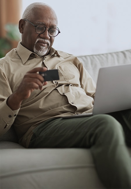 Veteran uses a laptop and holding a credit card to place an order.