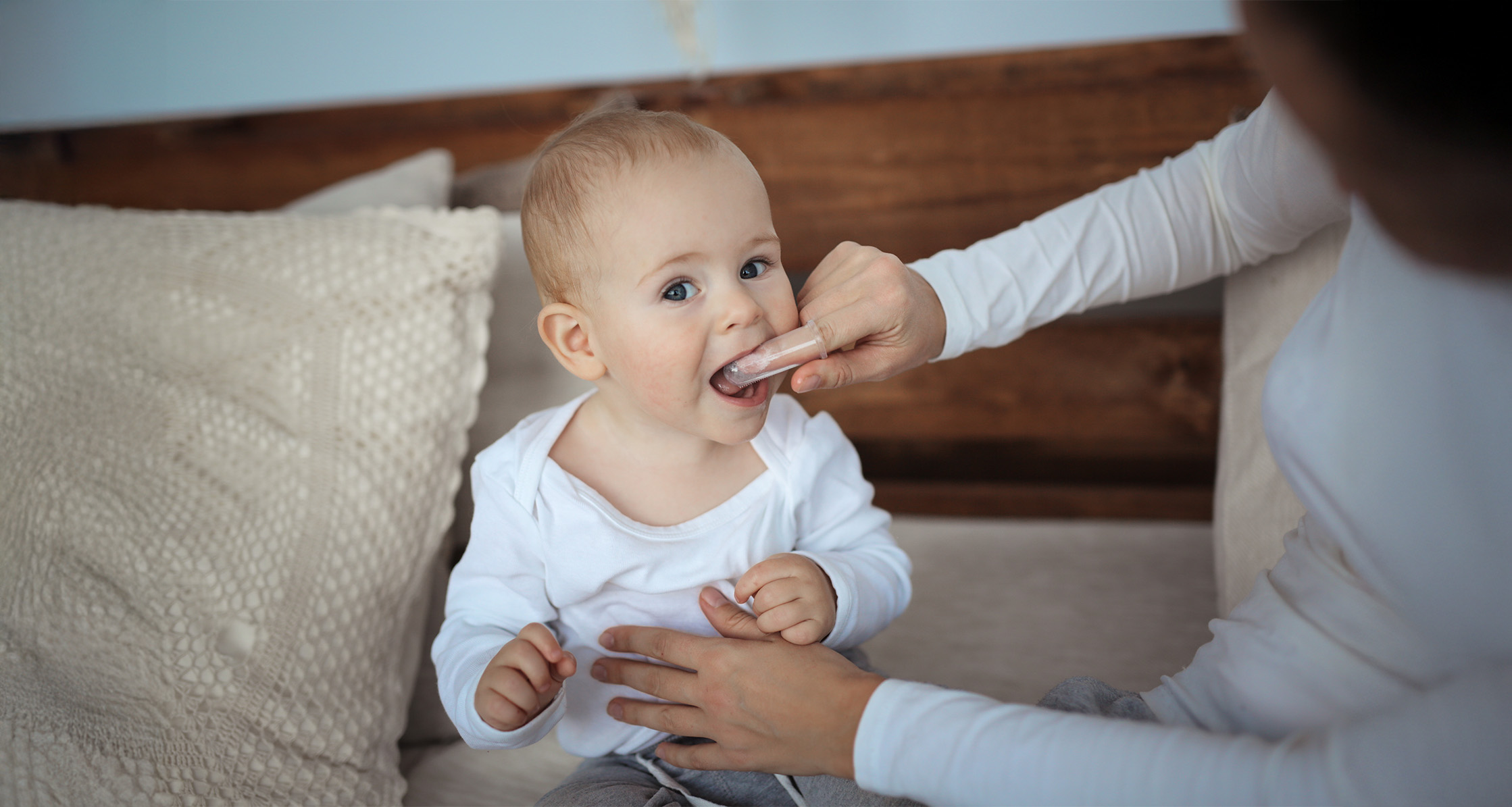 Mom brushes baby’s mouth with Soft Silicone Finger.