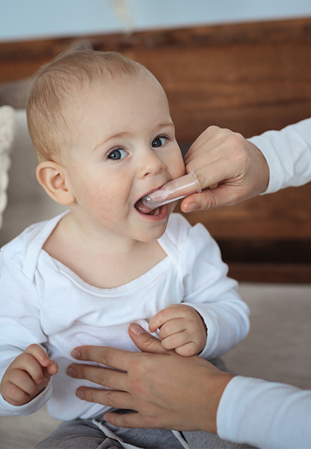Mom brushes baby’s mouth with Soft Silicone Finger.